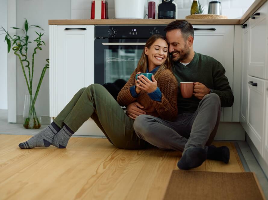 Loving couple enjoying in cup of coffee while relaxing on the floor in the kitchen.
