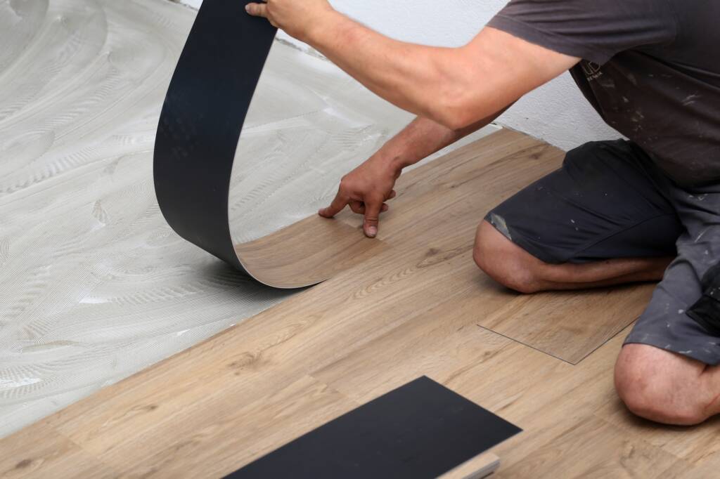 Worker installing new vinyl tile floor